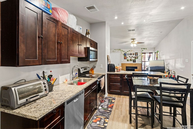 kitchen with stainless steel appliances, sink, light stone counters, light wood-type flooring, and ceiling fan