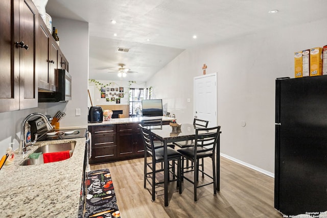 kitchen with light hardwood / wood-style flooring, ceiling fan, light stone countertops, appliances with stainless steel finishes, and dark brown cabinetry