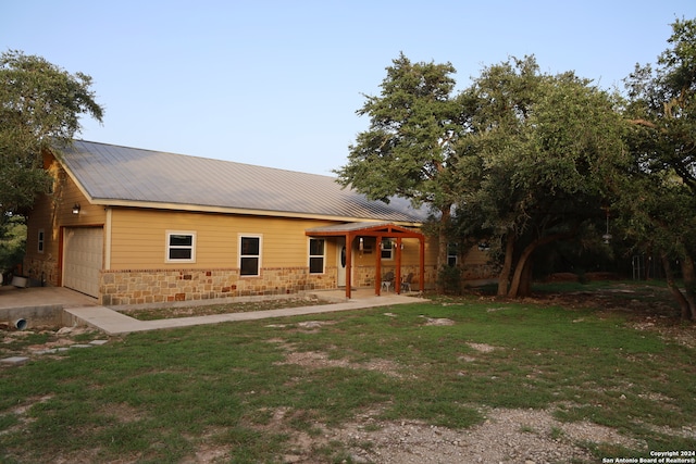 back of property featuring a lawn and a garage