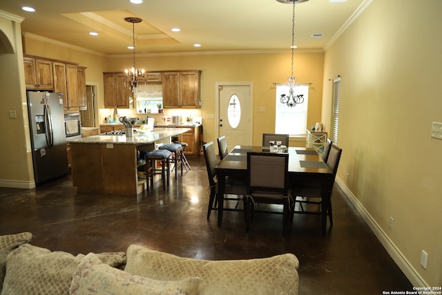 dining space with a raised ceiling, an inviting chandelier, and crown molding