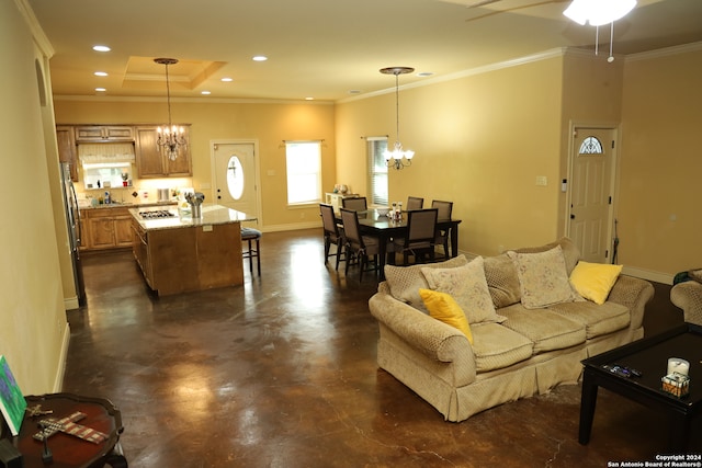 living room with a raised ceiling, ceiling fan with notable chandelier, and crown molding