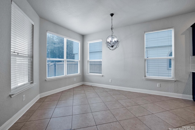 unfurnished room with tile patterned flooring, a notable chandelier, and a wealth of natural light