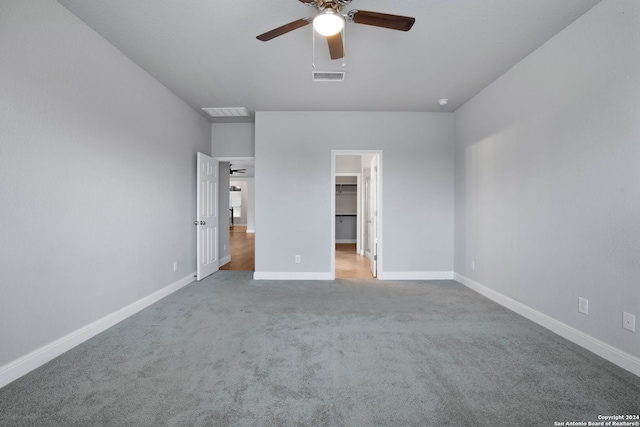 unfurnished bedroom featuring ceiling fan, light colored carpet, and a walk in closet