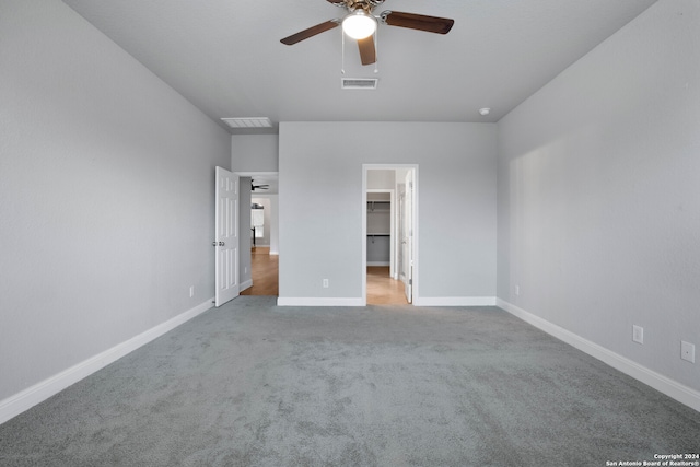 unfurnished bedroom featuring a walk in closet, ceiling fan, carpet flooring, and a closet