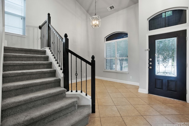 foyer entrance with tile patterned flooring, a towering ceiling, and a chandelier