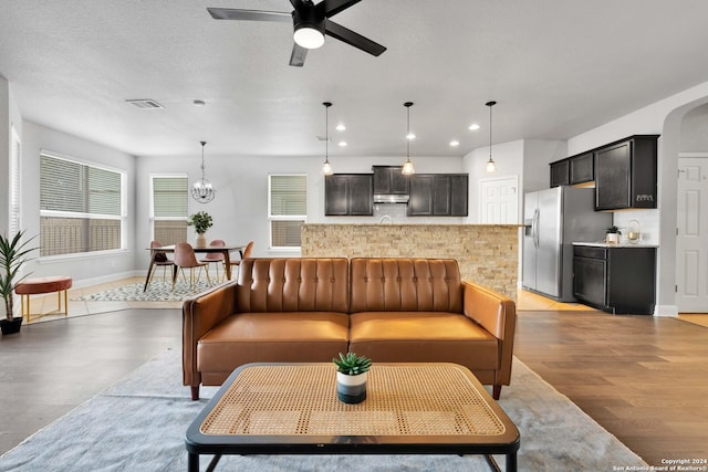 living room featuring ceiling fan, a wealth of natural light, a textured ceiling, and light hardwood / wood-style floors