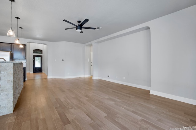 unfurnished living room with ceiling fan and light hardwood / wood-style flooring