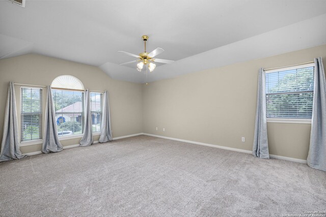 unfurnished bedroom with a spacious closet, a closet, lofted ceiling, light colored carpet, and ceiling fan