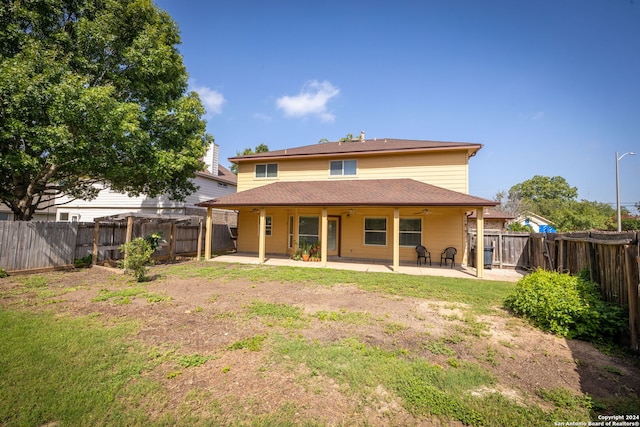 rear view of property with ceiling fan, a patio, and a yard