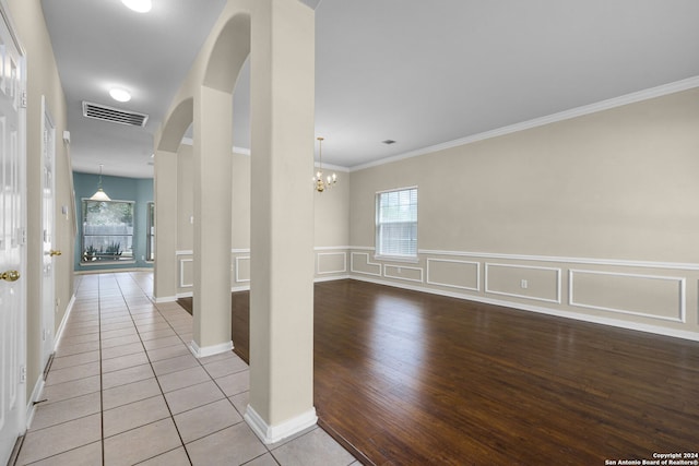 hallway with light tile patterned flooring, an inviting chandelier, and ornamental molding