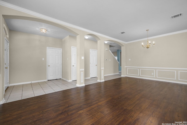 spare room featuring a chandelier, light wood-type flooring, and crown molding