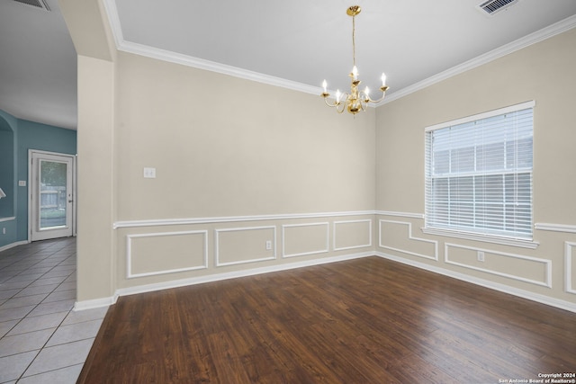 unfurnished room with tile patterned flooring, a notable chandelier, crown molding, and a wealth of natural light