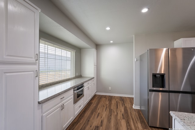 kitchen with dark wood-type flooring, light stone counters, appliances with stainless steel finishes, and white cabinets