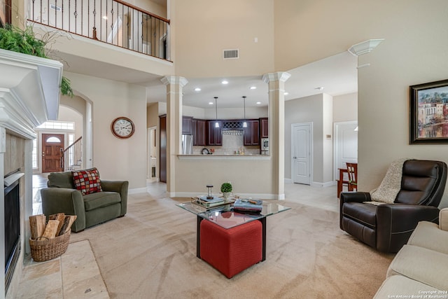 carpeted living room featuring ornate columns and a high ceiling