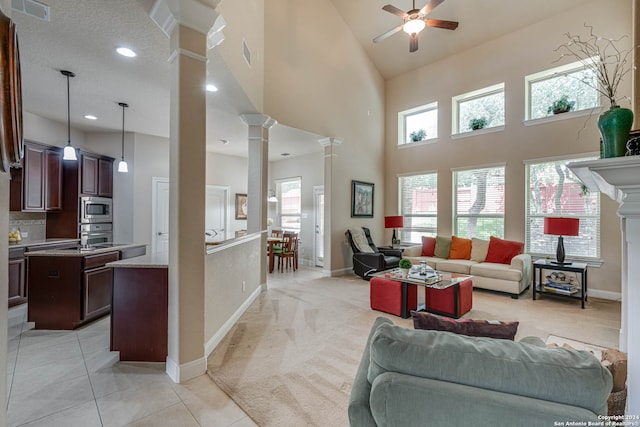 living room featuring a textured ceiling, ceiling fan, ornate columns, light carpet, and high vaulted ceiling