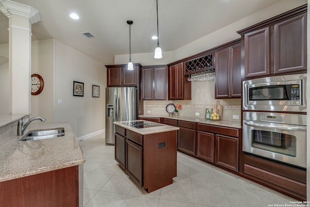 kitchen with stainless steel appliances, decorative backsplash, sink, decorative columns, and light stone countertops