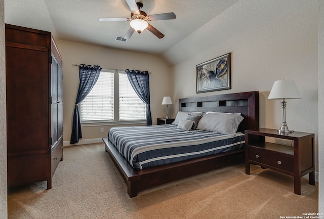 bedroom with a textured ceiling, vaulted ceiling, light colored carpet, and ceiling fan