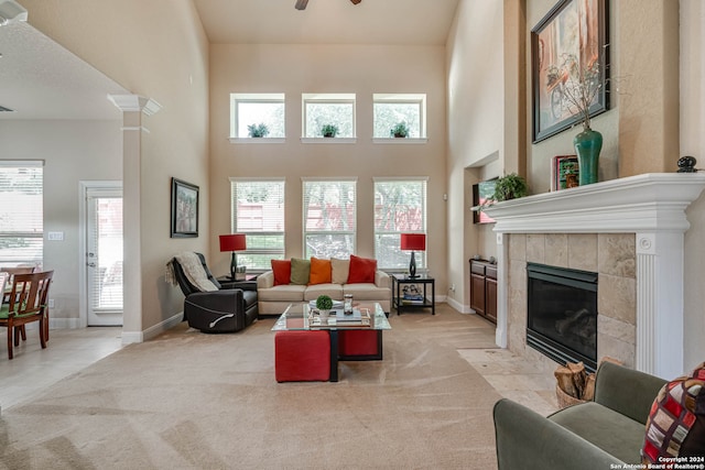 living room featuring a high ceiling, a fireplace, light carpet, and a wealth of natural light