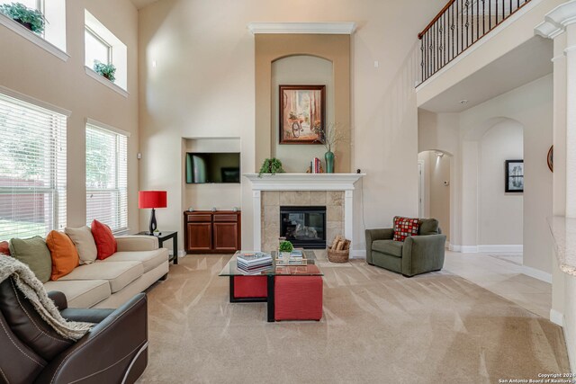 living room with a fireplace, light colored carpet, and a towering ceiling