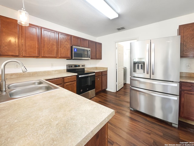 kitchen featuring sink, dark hardwood / wood-style flooring, stainless steel appliances, and decorative light fixtures