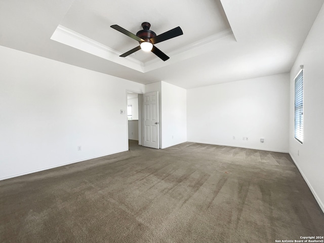 carpeted empty room with ceiling fan and a tray ceiling