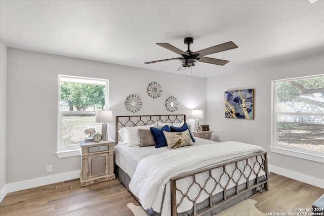 bedroom with light hardwood / wood-style floors, multiple windows, and ceiling fan