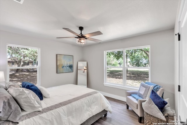 bedroom with multiple windows, wood-type flooring, and ceiling fan