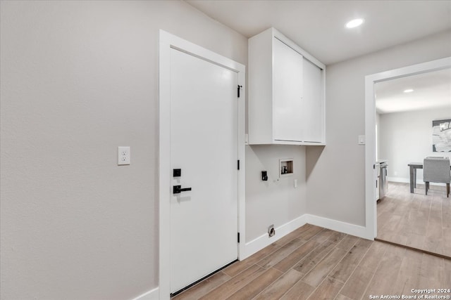 washroom with hookup for an electric dryer, cabinets, light hardwood / wood-style flooring, and washer hookup