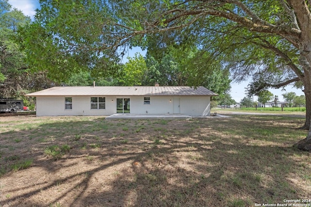 back of house with a patio and a lawn