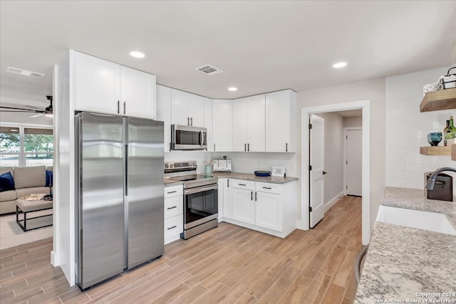 kitchen with appliances with stainless steel finishes, white cabinets, ceiling fan, and sink