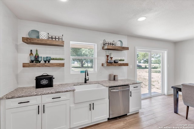 kitchen featuring sink, dishwasher, a wealth of natural light, and white cabinets