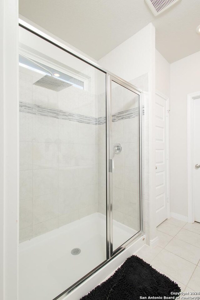 bathroom with a shower with door and tile patterned flooring