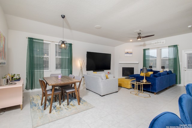 interior space with vaulted ceiling, a tile fireplace, and ceiling fan