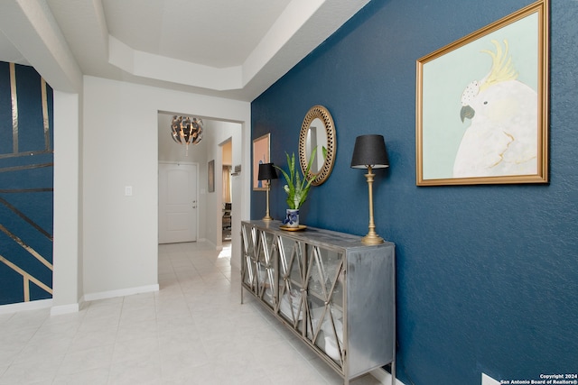 hallway featuring tile patterned floors and a tray ceiling