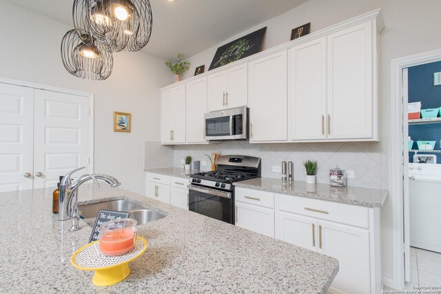 kitchen with washer / dryer, appliances with stainless steel finishes, white cabinets, and backsplash