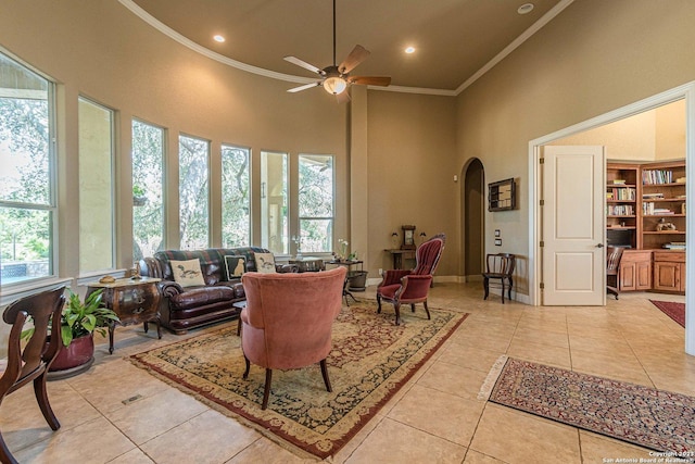 tiled living room featuring ceiling fan, crown molding, a healthy amount of sunlight, and a high ceiling