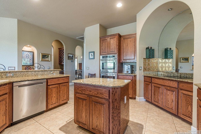 kitchen featuring light stone counters, light tile patterned floors, a kitchen island, and appliances with stainless steel finishes