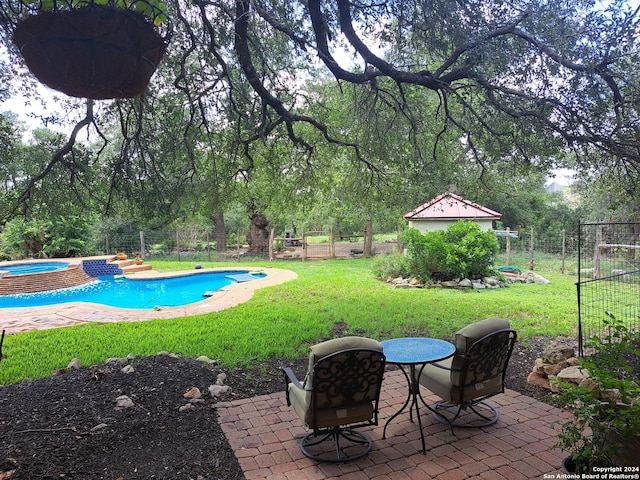 view of swimming pool featuring an in ground hot tub, a yard, a patio, and an outbuilding