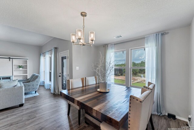 dining space with hardwood / wood-style flooring, a notable chandelier, and a textured ceiling