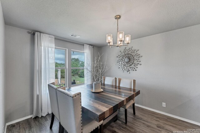 dining area with dark wood-type flooring, a notable chandelier, and a textured ceiling