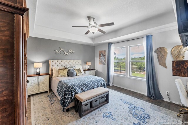 bedroom featuring hardwood / wood-style floors, ceiling fan, and a tray ceiling