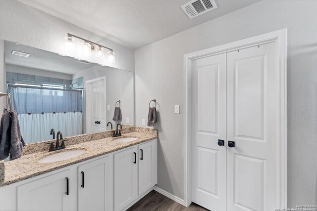 bathroom with vanity, hardwood / wood-style flooring, a textured ceiling, and walk in shower