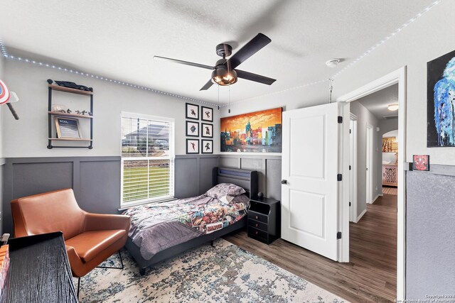 bedroom featuring dark hardwood / wood-style flooring, ceiling fan, and a textured ceiling