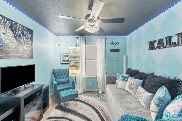 living room featuring ceiling fan, wood-type flooring, and a textured ceiling