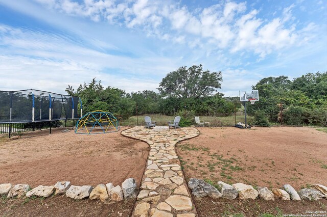 view of yard featuring a trampoline and an outdoor fire pit