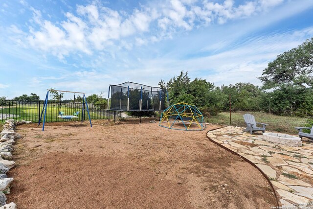 view of playground with a trampoline and an outdoor fire pit