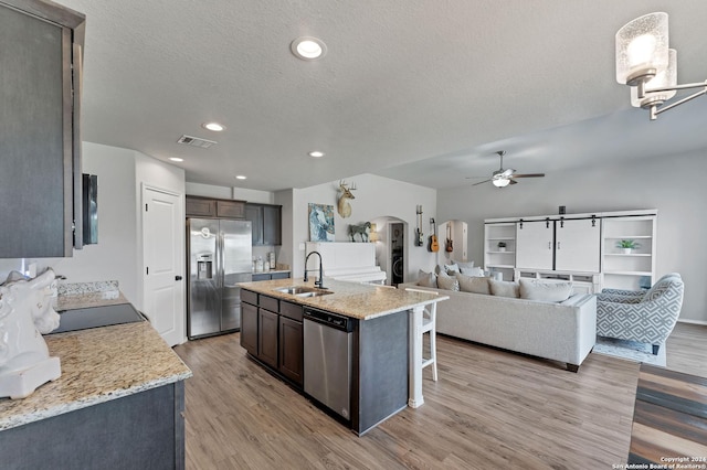 kitchen featuring sink, appliances with stainless steel finishes, hanging light fixtures, dark brown cabinets, and light stone countertops