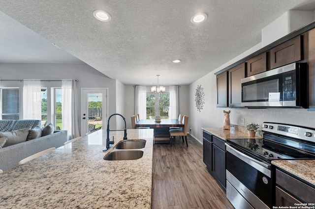 kitchen with a breakfast bar area, light stone counters, dark brown cabinets, a center island with sink, and appliances with stainless steel finishes