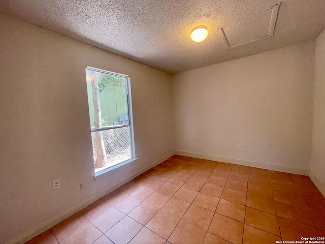 tiled empty room featuring a textured ceiling