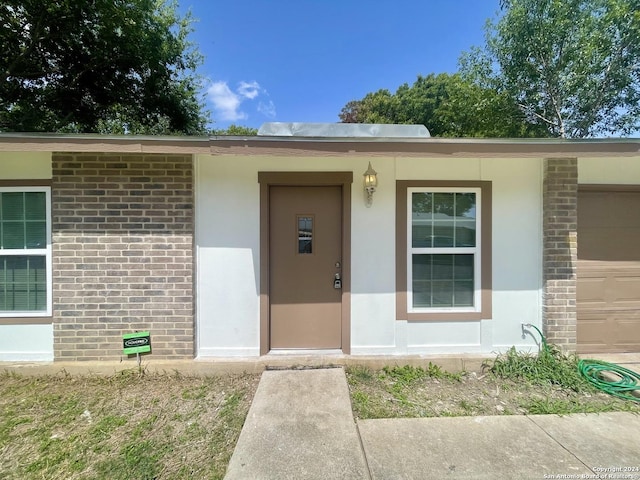 doorway to property featuring brick siding and stucco siding